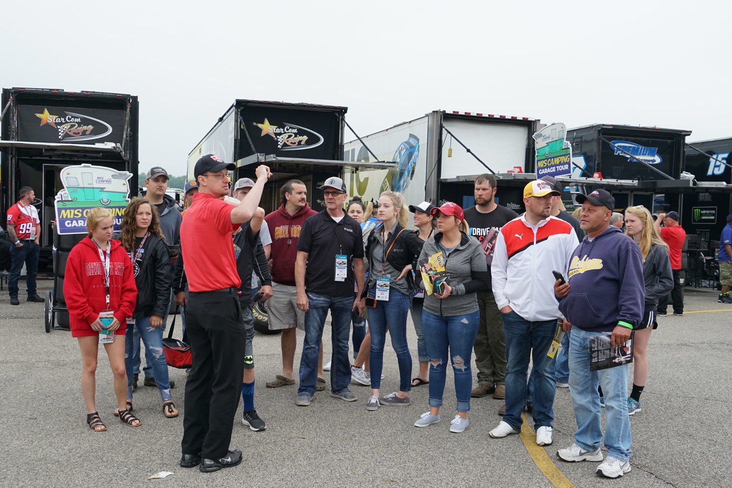 A man in a red shirt is talking to a group of people