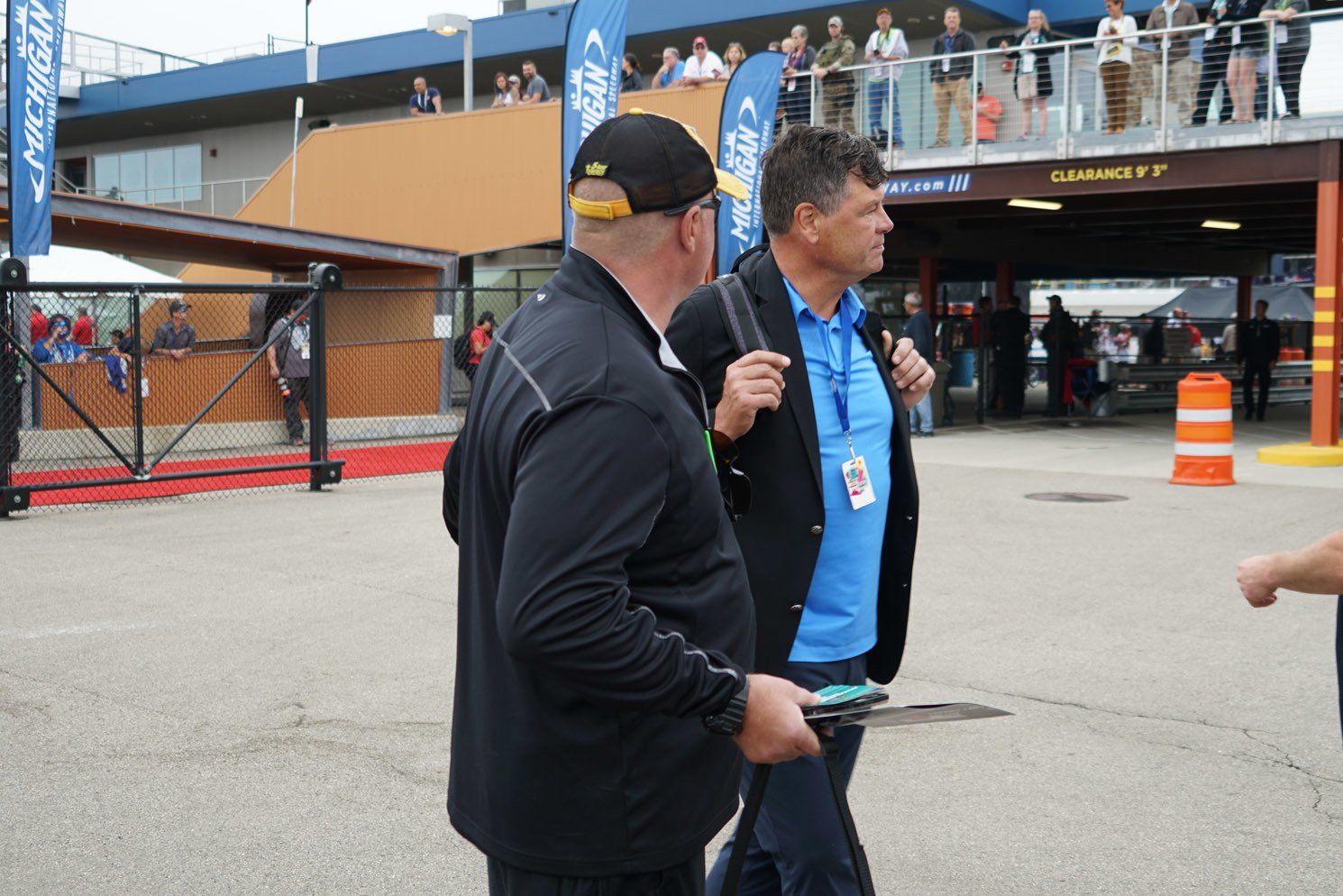 A man in a blue shirt is walking with a man in a black jacket