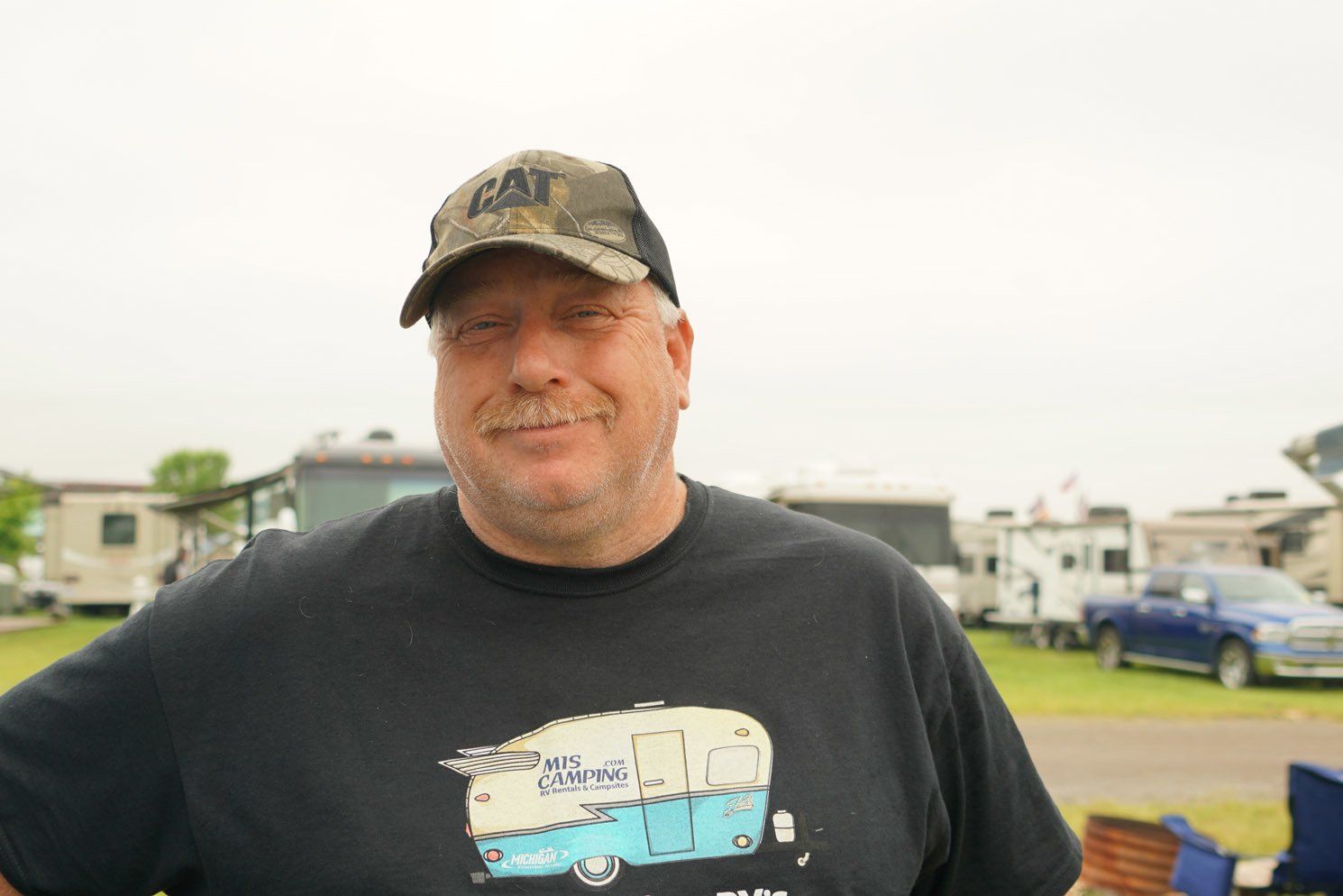 A man wearing a hat and a black shirt with a picture of a trailer on it.