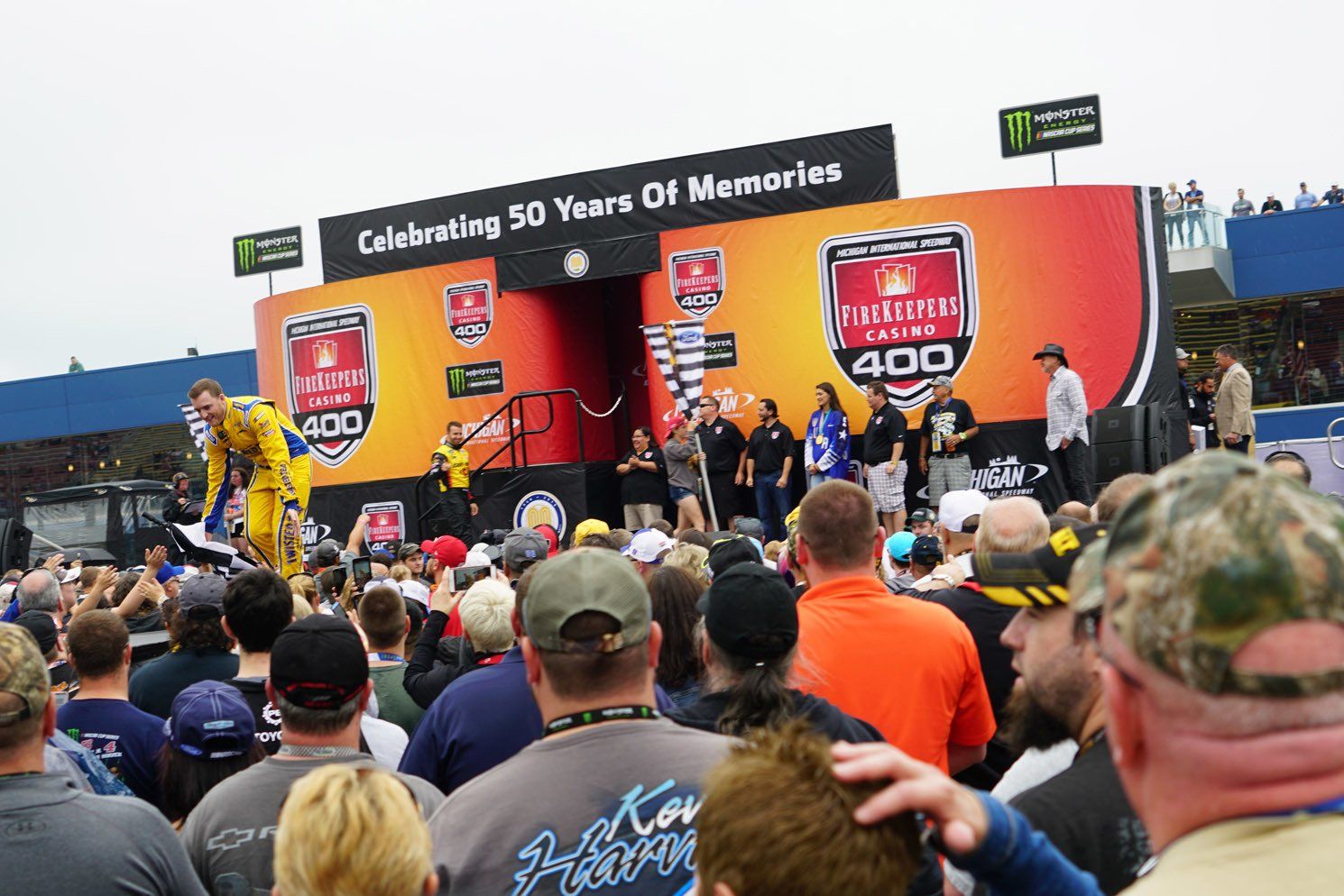 A crowd of people are gathered in front of a stage that says celebrating 50 years of memories