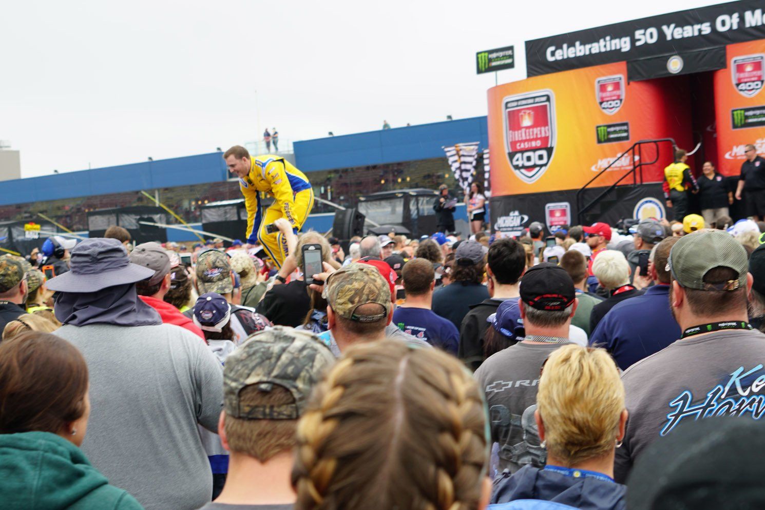 A crowd of people watching a man in a yellow suit on a stage