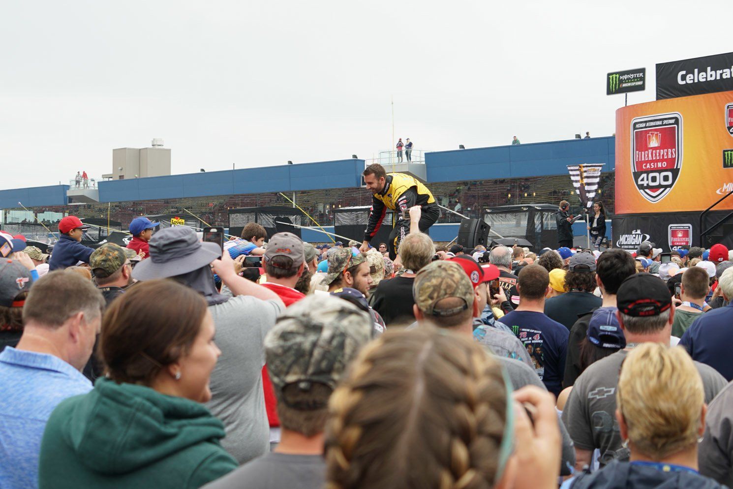 A crowd of people are watching a race at a race track.