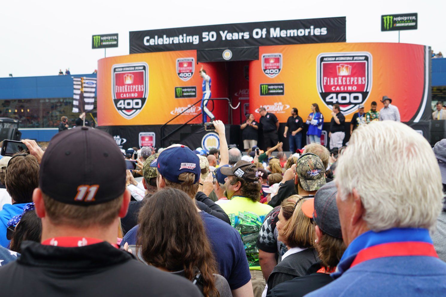 A crowd of people are gathered in front of a stage that says celebrating 50 years of memories