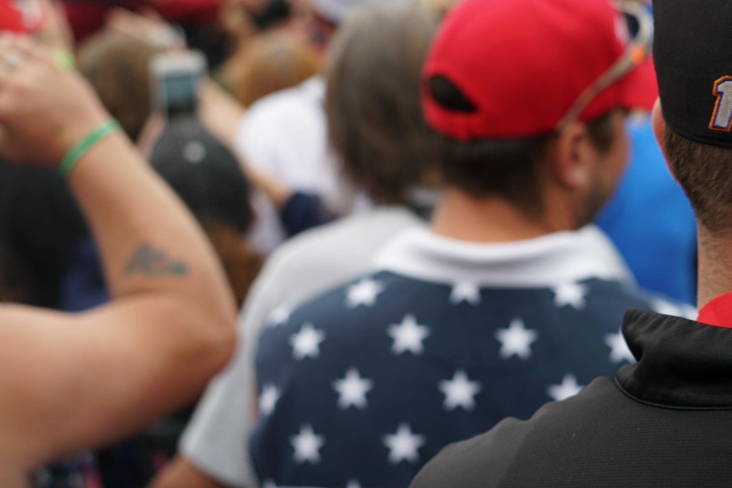 A man wearing an american flag shirt is standing in a crowd