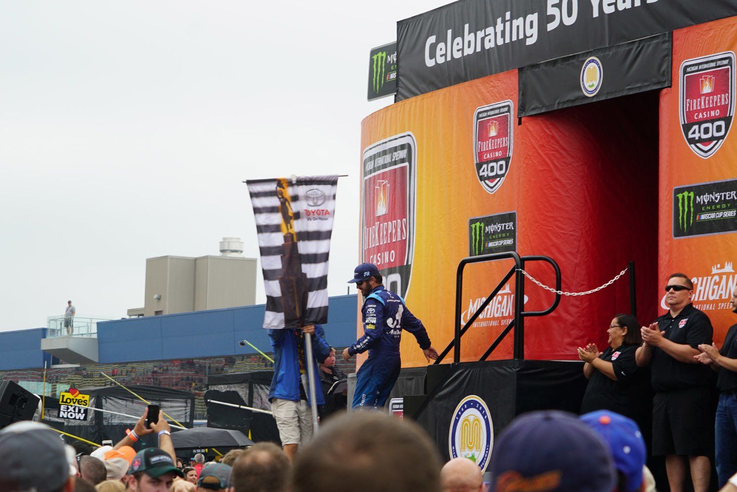 A man stands on a stage in front of a sign that says celebrating 50 years