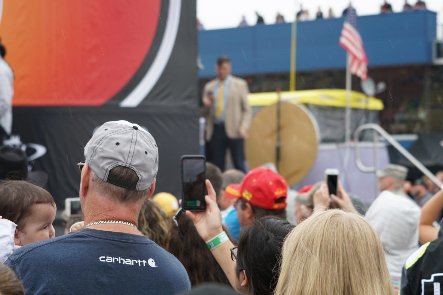 A man in a carhartt shirt is taking a picture of a crowd
