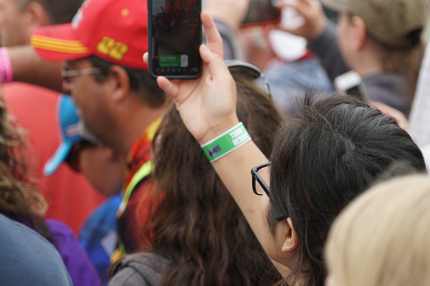 A woman is taking a picture of a crowd with her phone