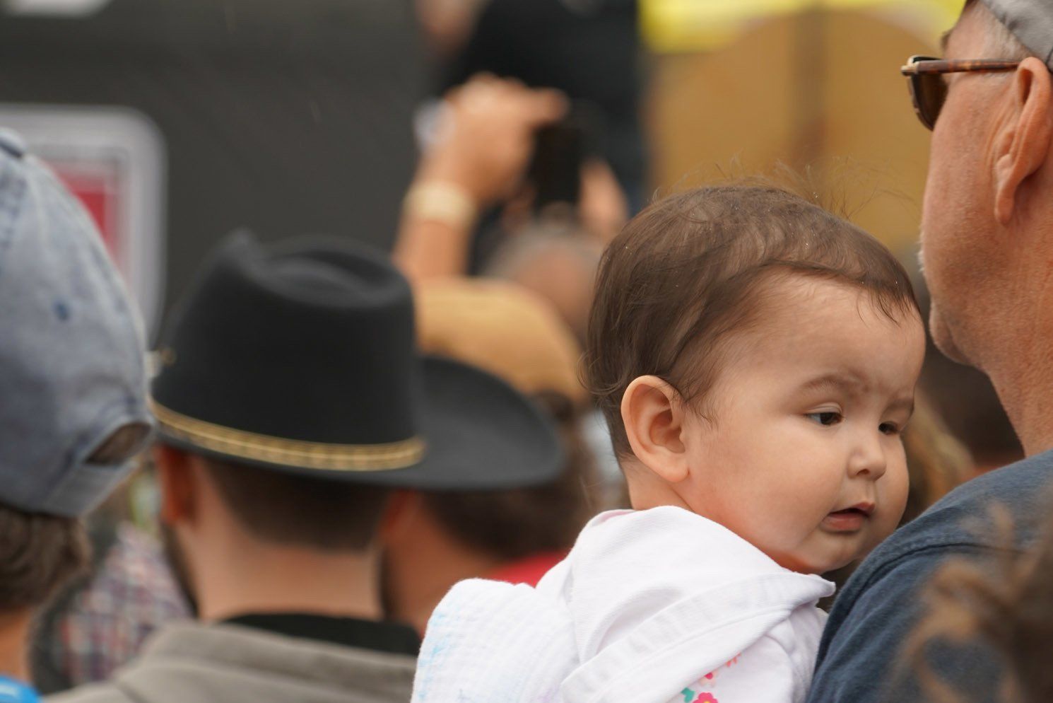 A baby is being held by a man in a crowd