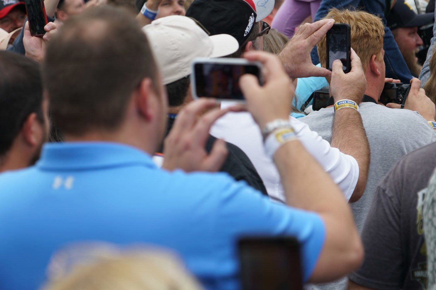 A crowd of people are taking pictures with their cell phones
