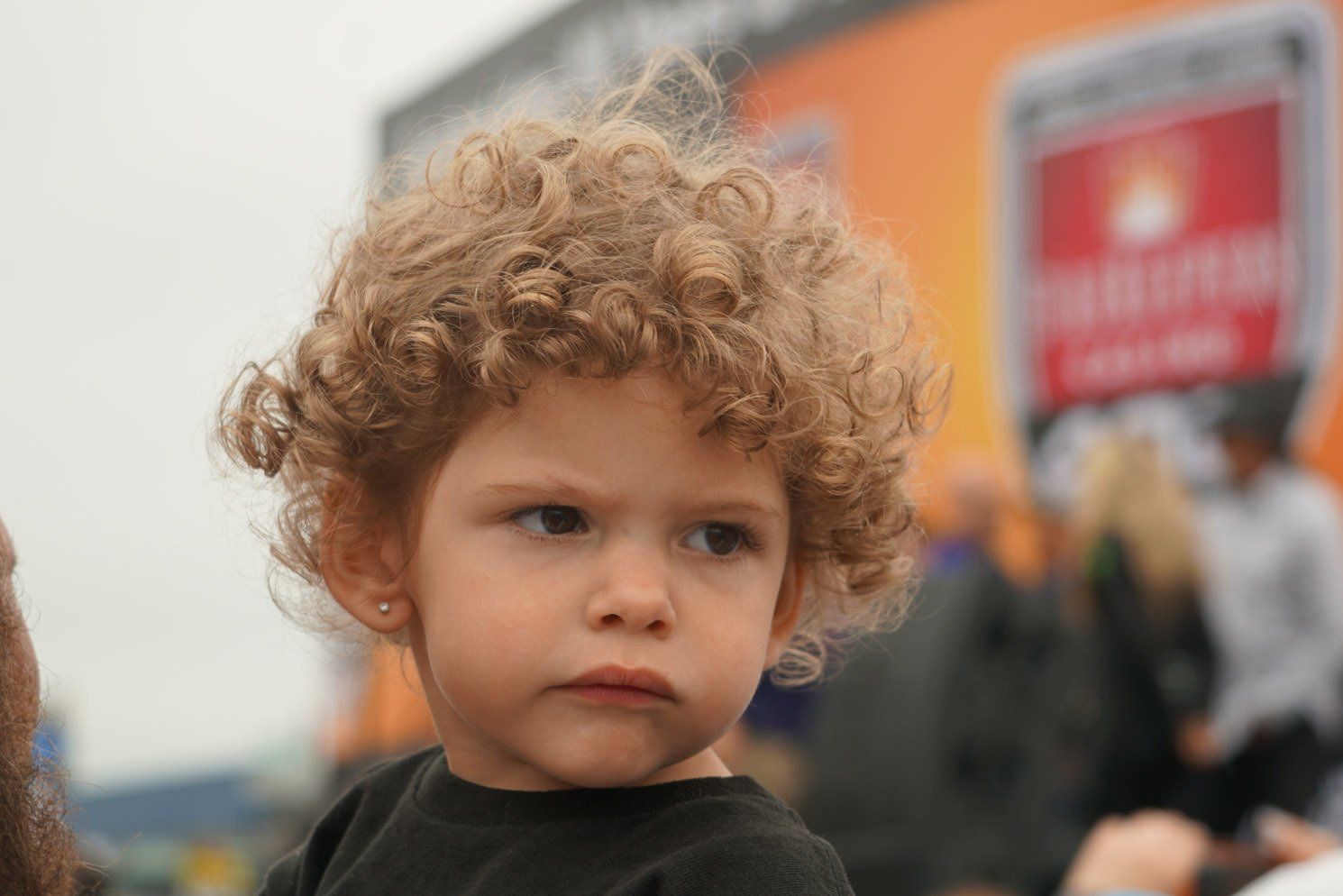 A little girl with curly hair looks at the camera