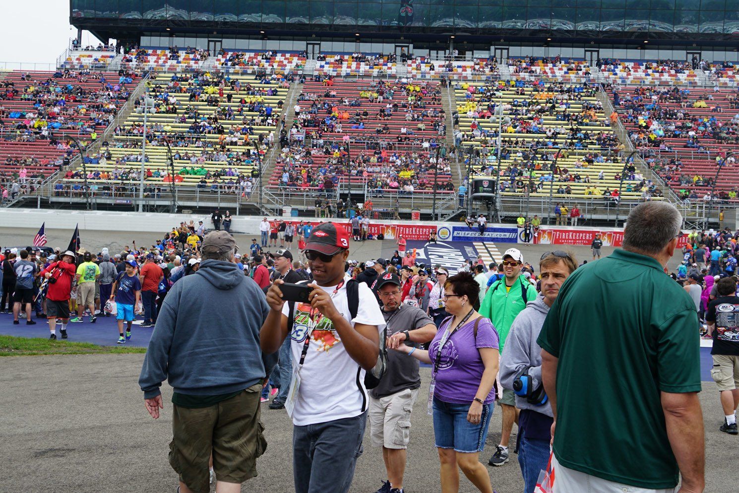 A man is taking a picture of a crowd at a race track.