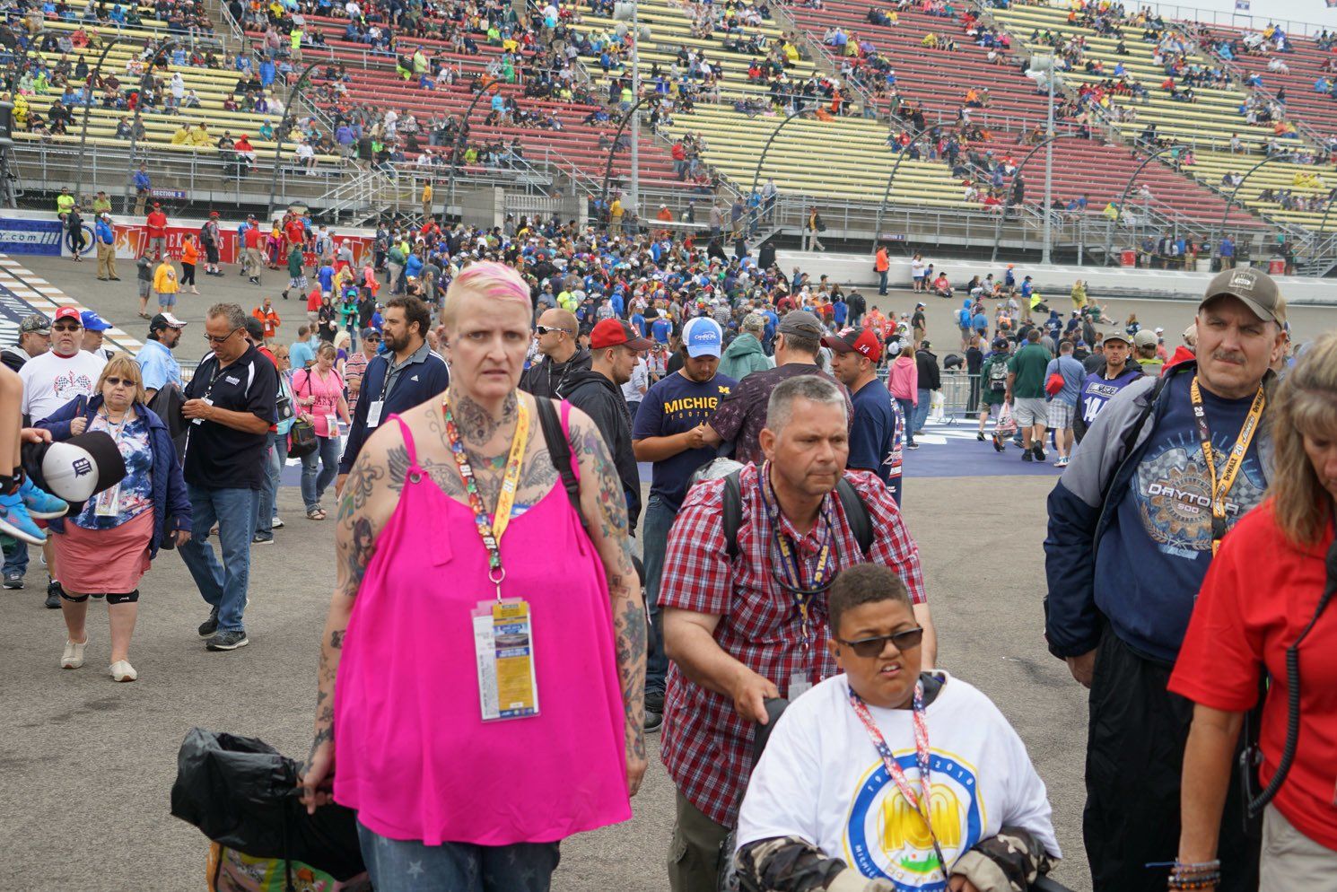 A woman in a pink top is walking with a child in a wheelchair