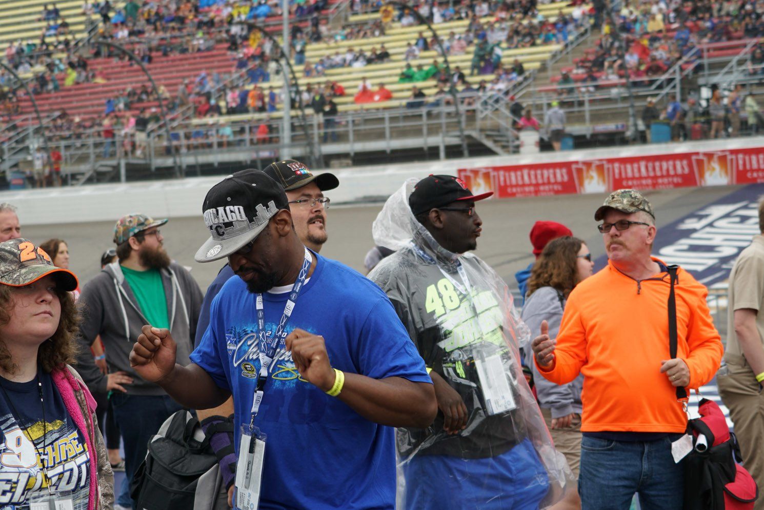 A group of people are standing in a stadium watching a race.