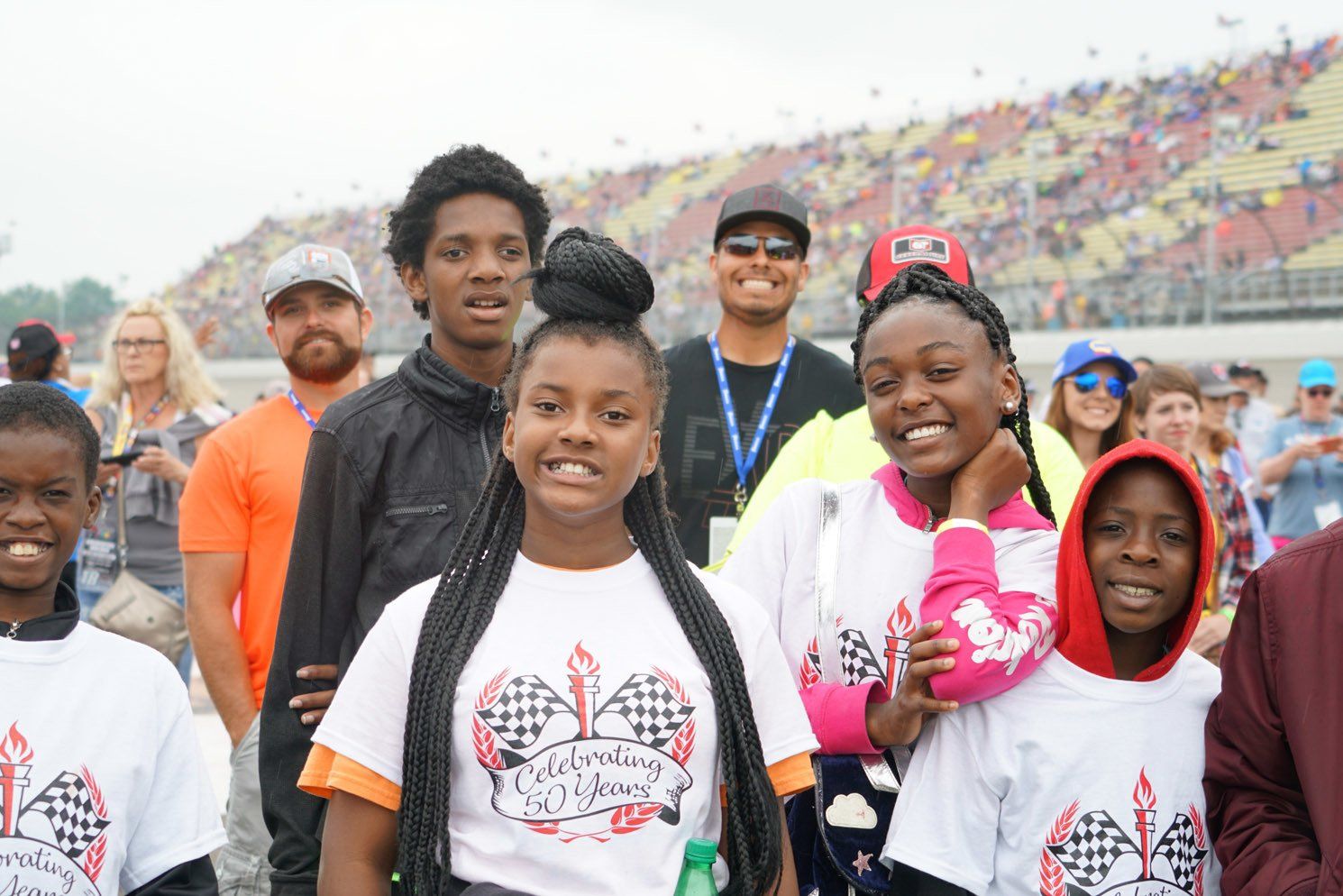 A group of young people are posing for a picture at a race track.