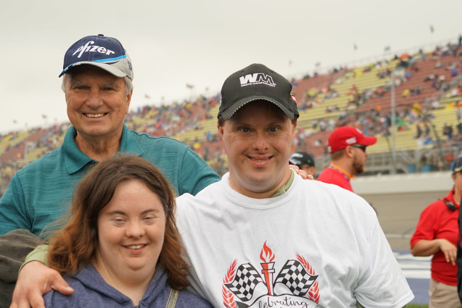 Three people posing for a picture one of whom is wearing a shirt with a checkered flag on it