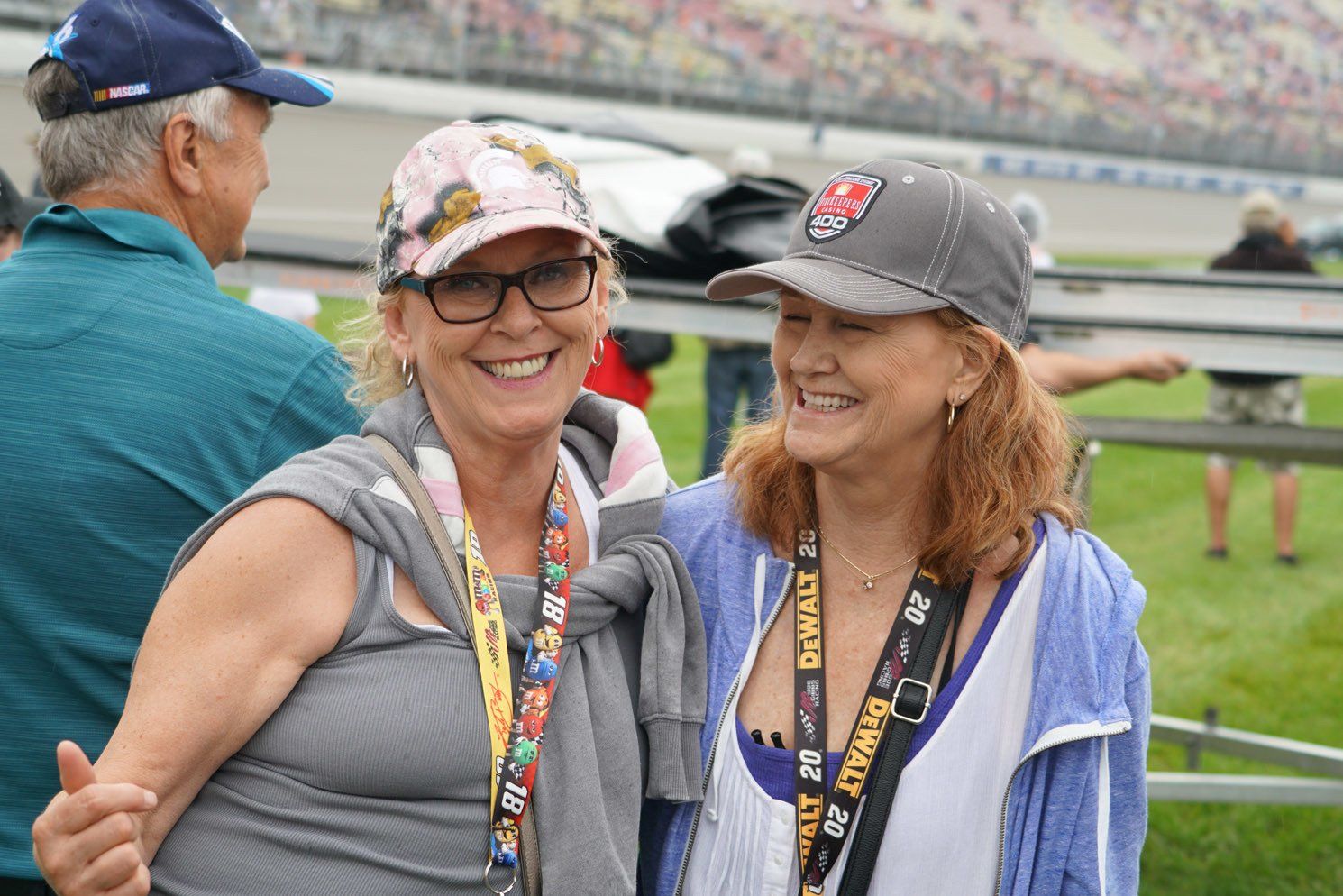 Two women are posing for a picture at a race track.