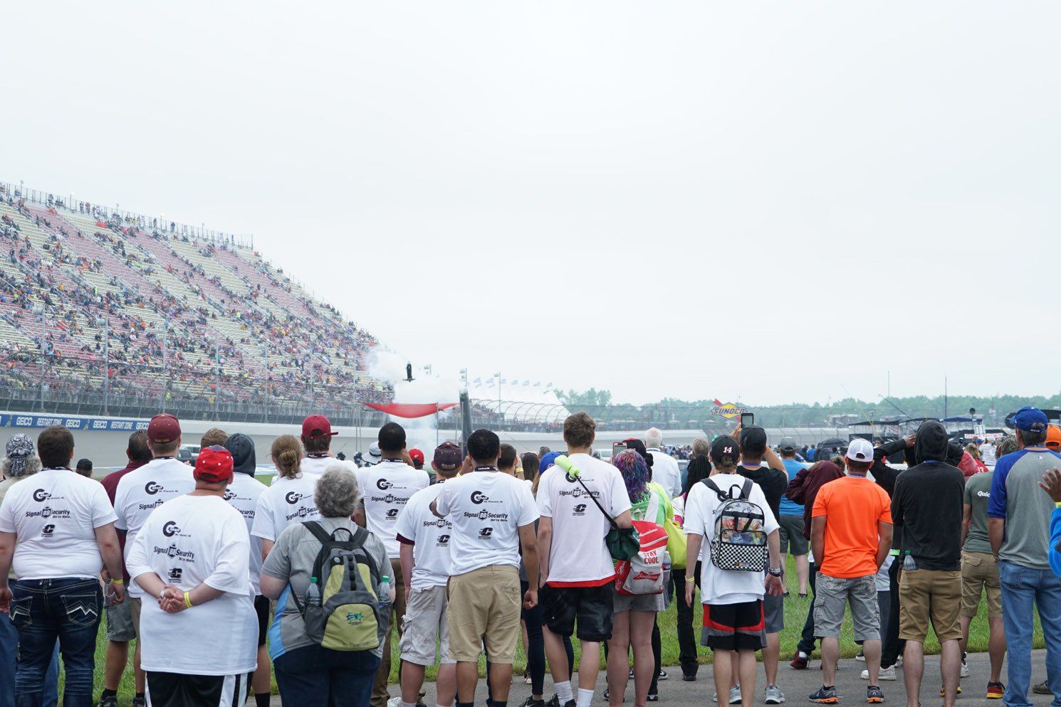 A large group of people are standing in a stadium watching a race.