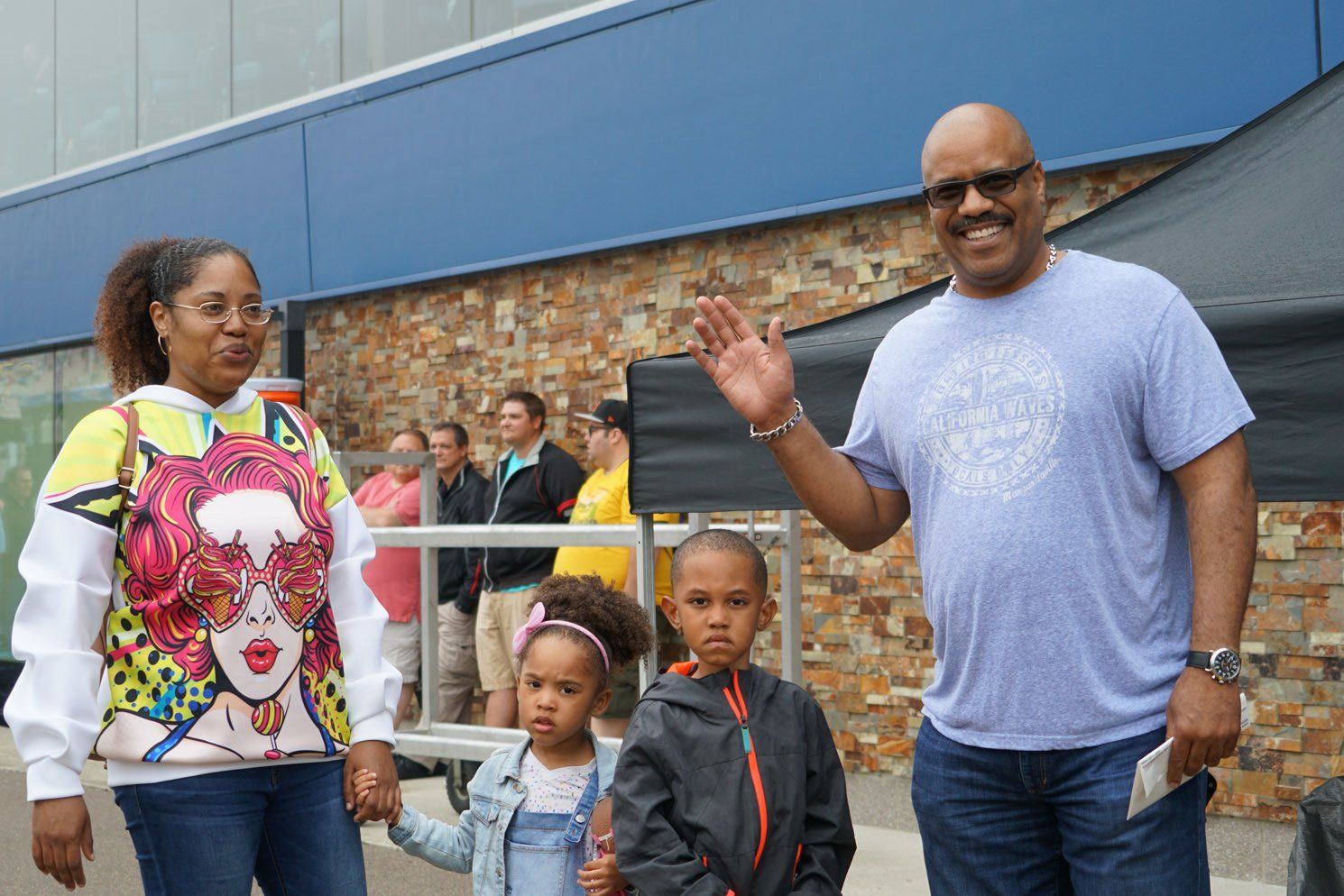 A man , woman and two children are standing in front of a building.