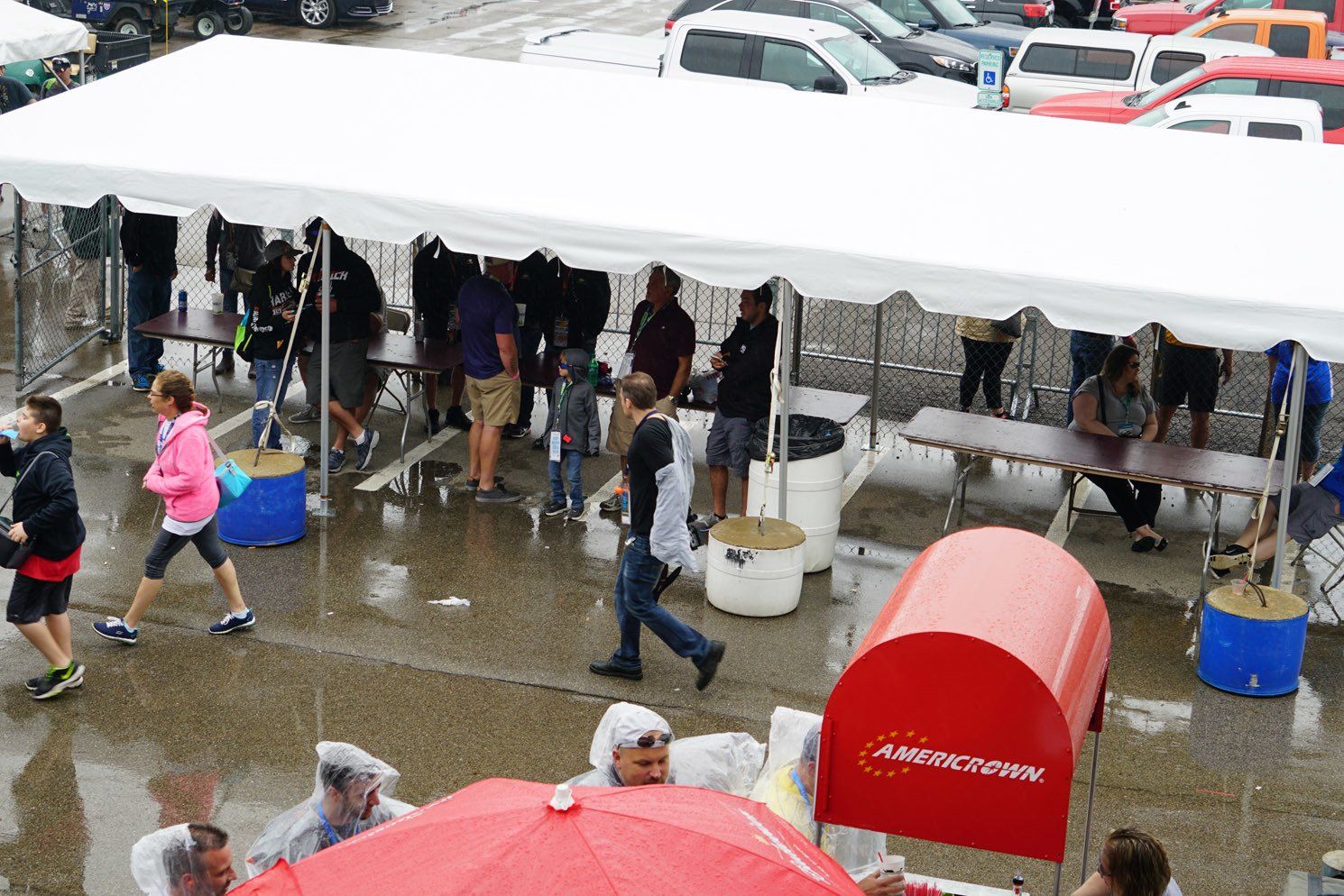 A group of people are gathered under a tent in the rain