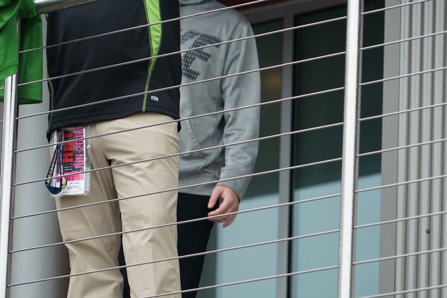 Two men are standing on a balcony looking out a window.