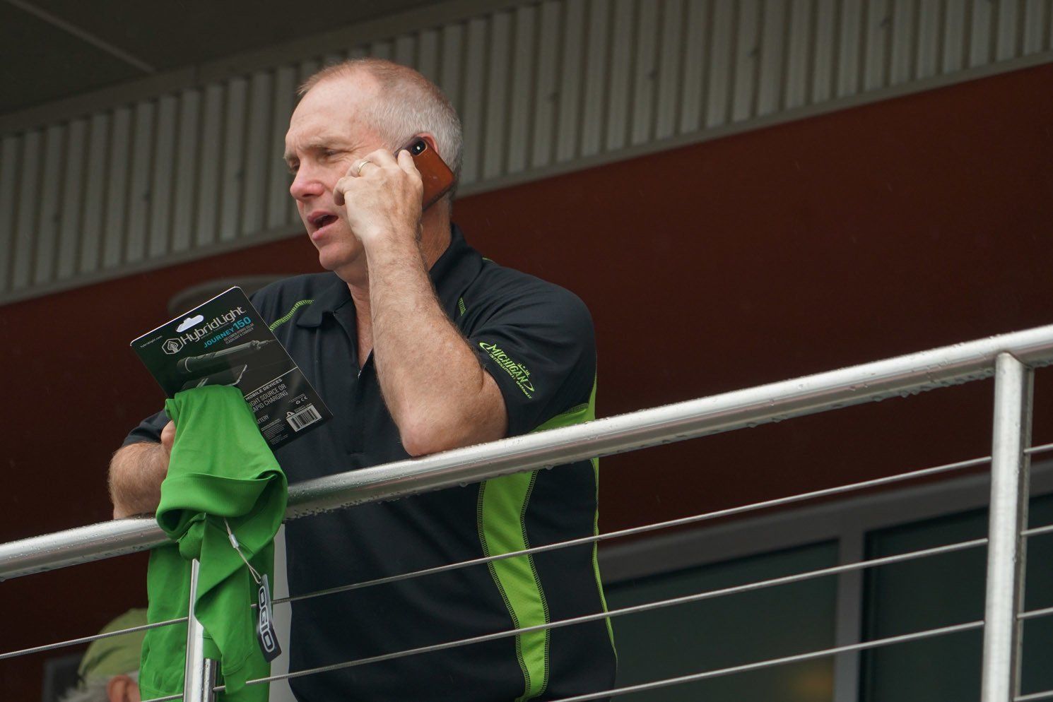 A man talking on a cell phone while standing on a balcony