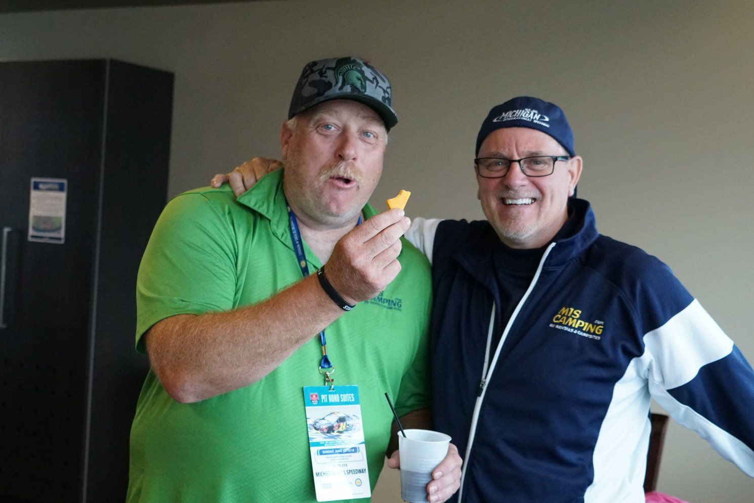 Two men are posing for a picture and one is holding a french fry