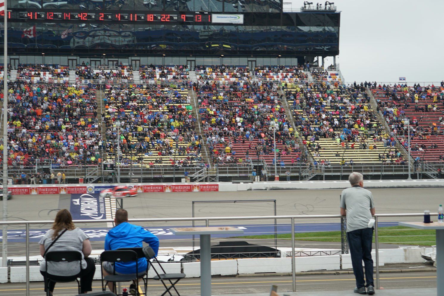 A crowd of people are watching a race at a race track.