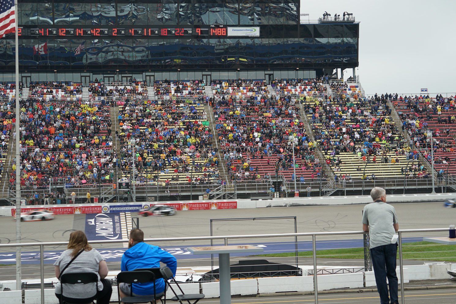 A crowd of people are watching a race at a race track.
