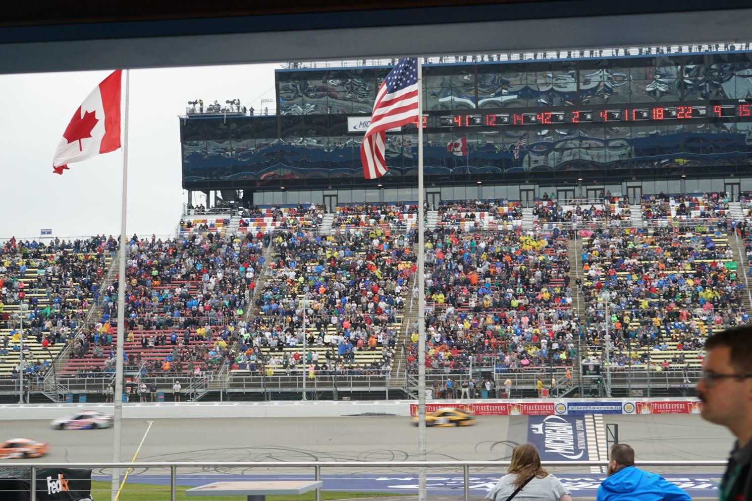 A canadian flag and an american flag are flying at a race track