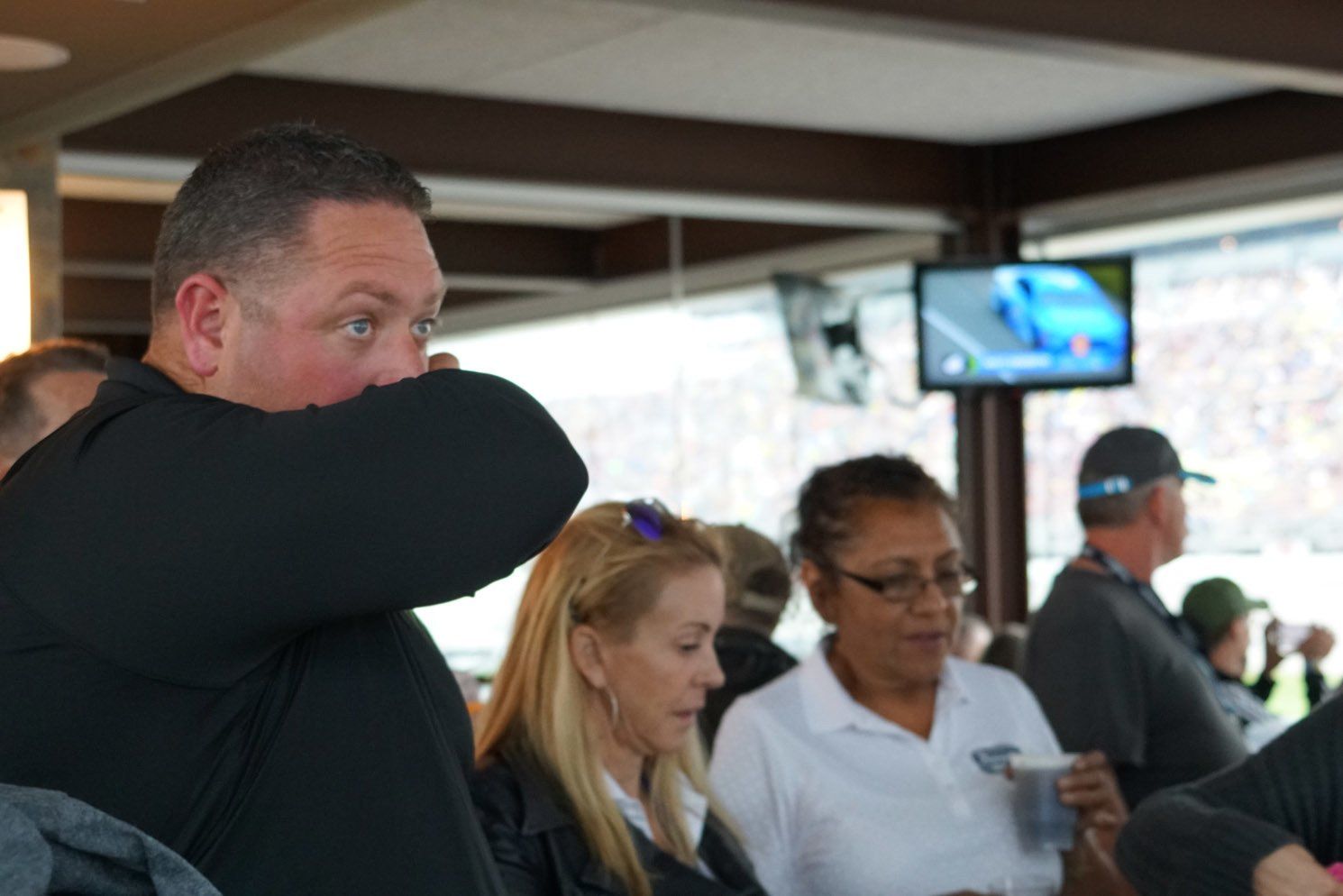 A group of people sitting in a room with a man covering his mouth