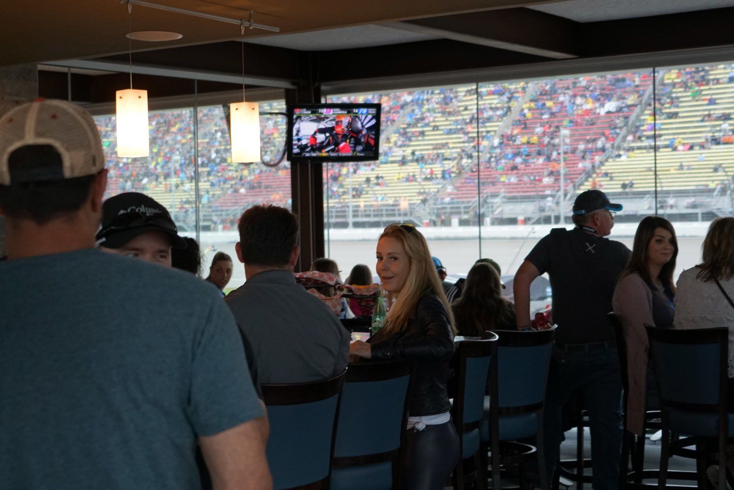 A group of people are sitting at tables in a restaurant watching a race.