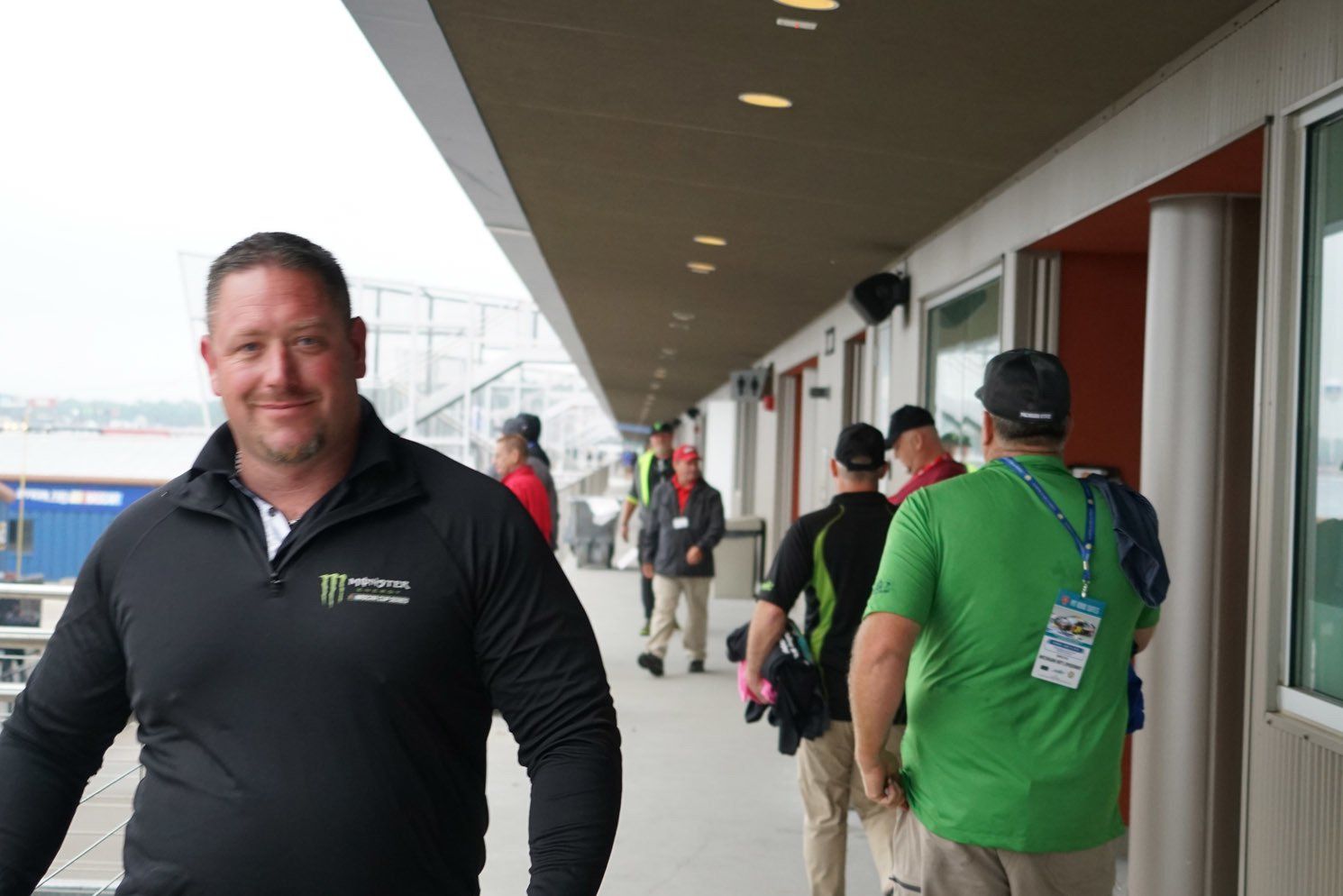 A man in a black jacket is walking down a hallway