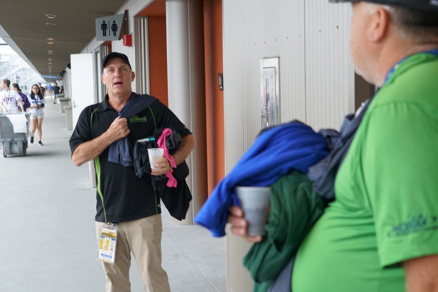 A man in a black shirt is talking to another man in a green shirt