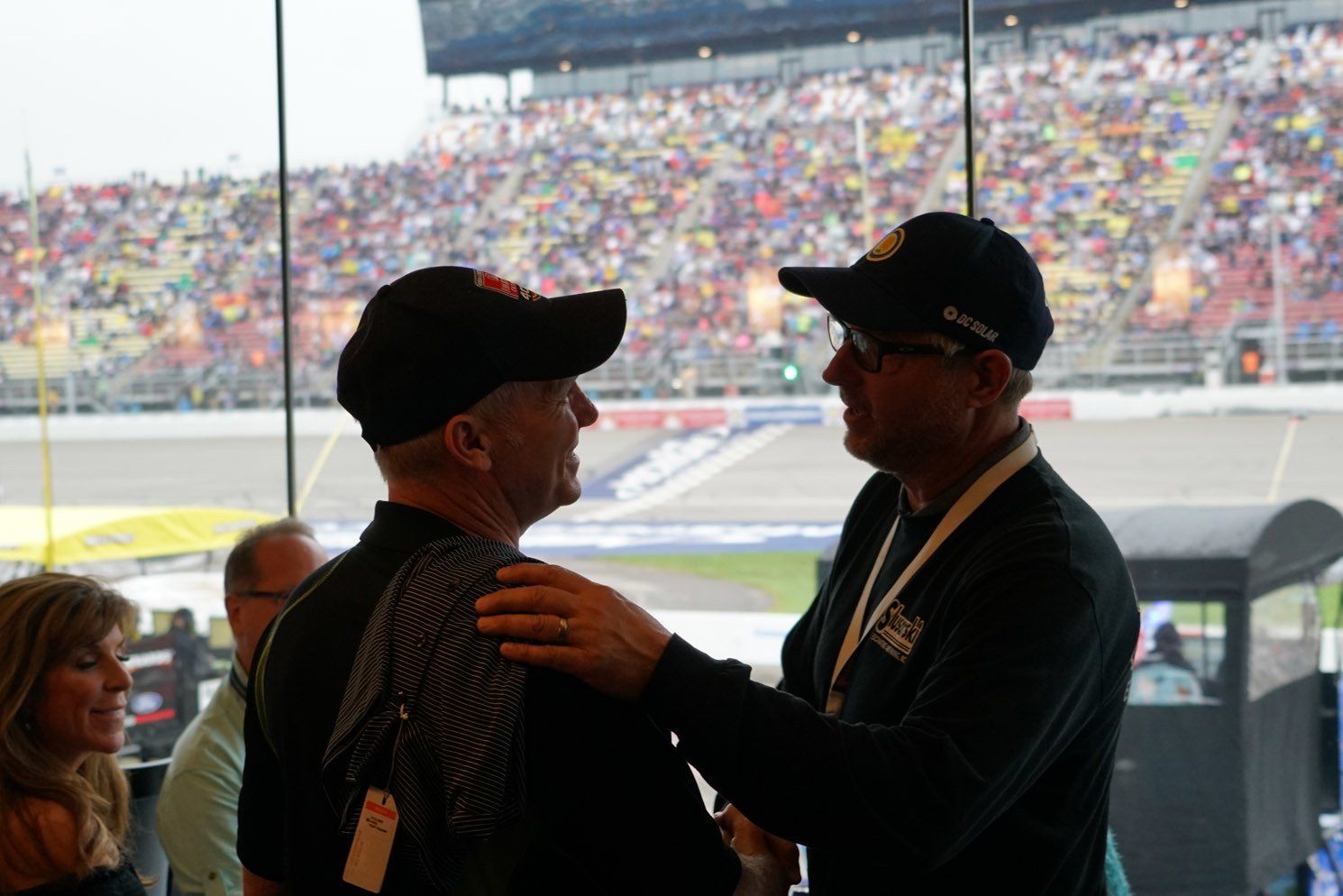 Two men are talking to each other in front of a stadium.