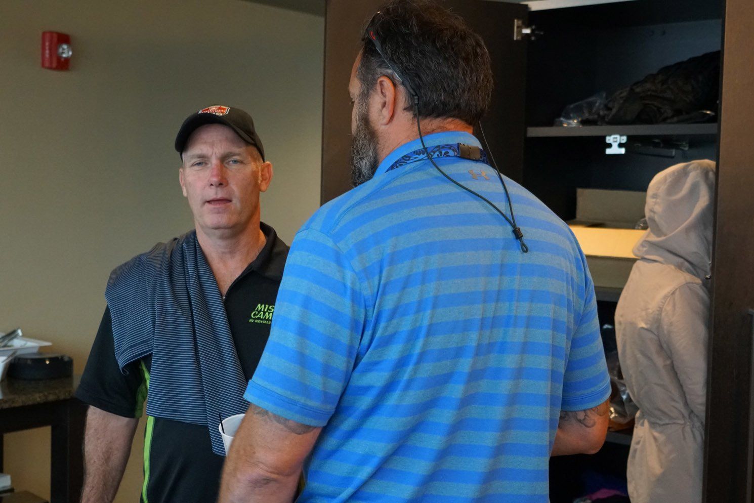 A man in a blue shirt is talking to another man