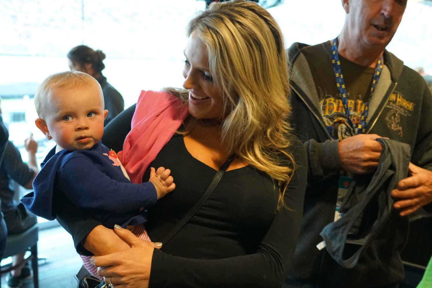 A woman is holding a baby in her arms while a man stands behind her