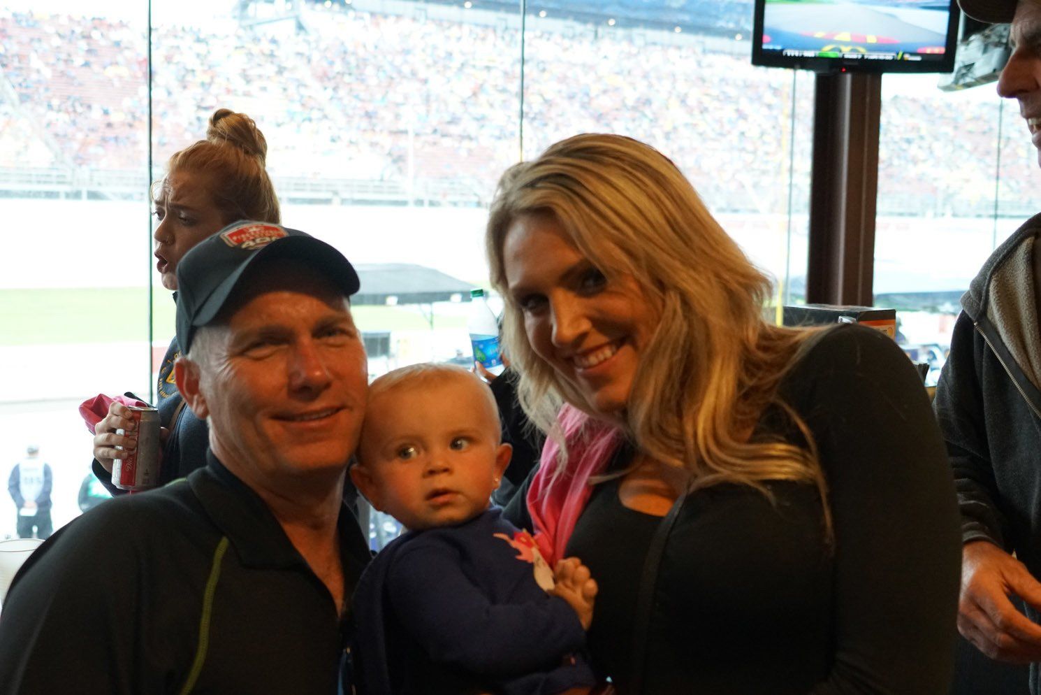 A man and woman are holding a baby and smiling for the camera