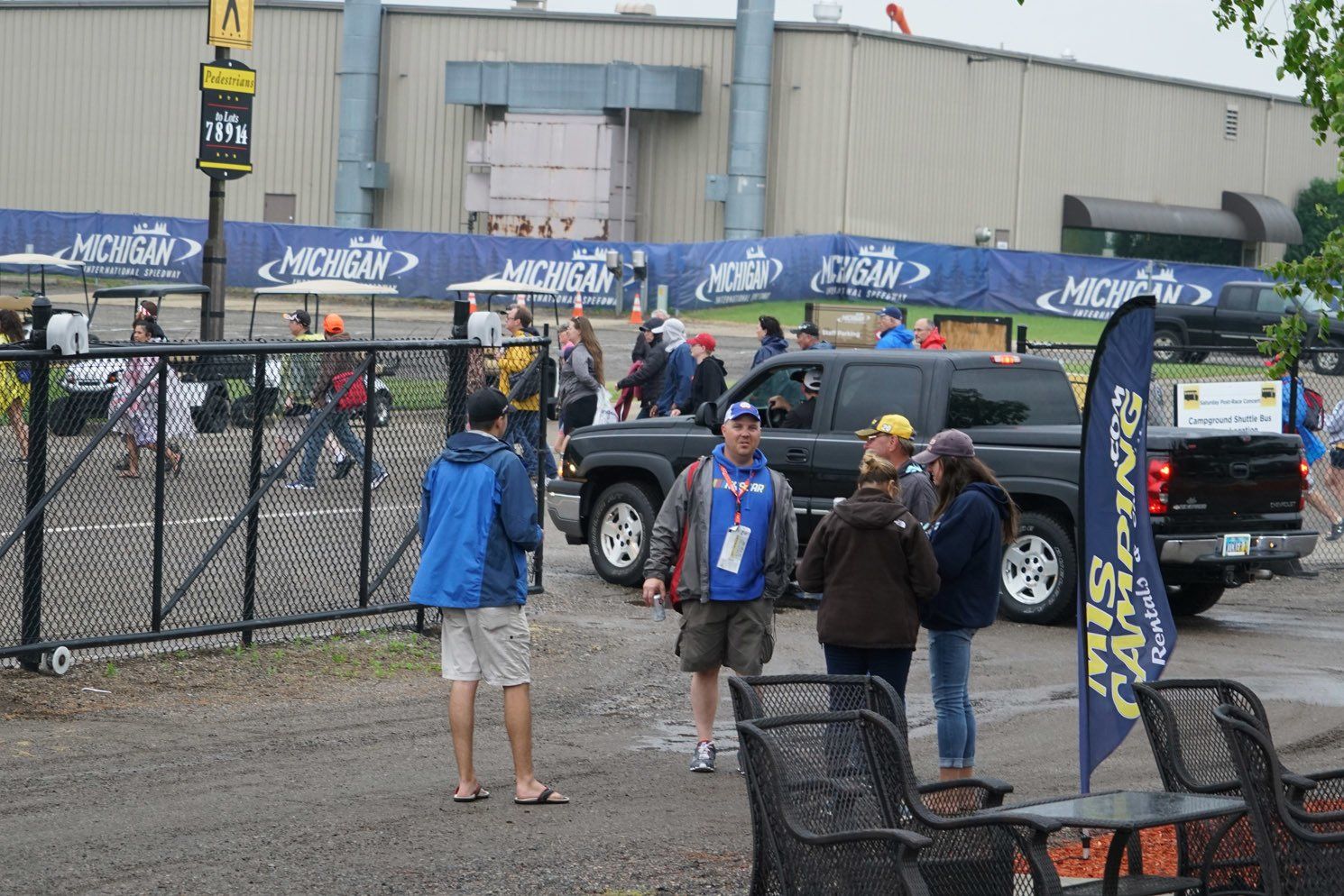 A group of people are standing in a parking lot in front of a building.