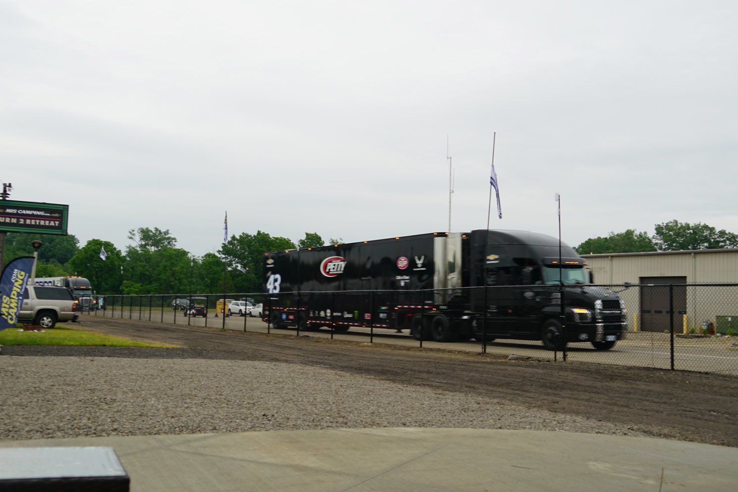 A black semi truck is parked in a gravel lot.