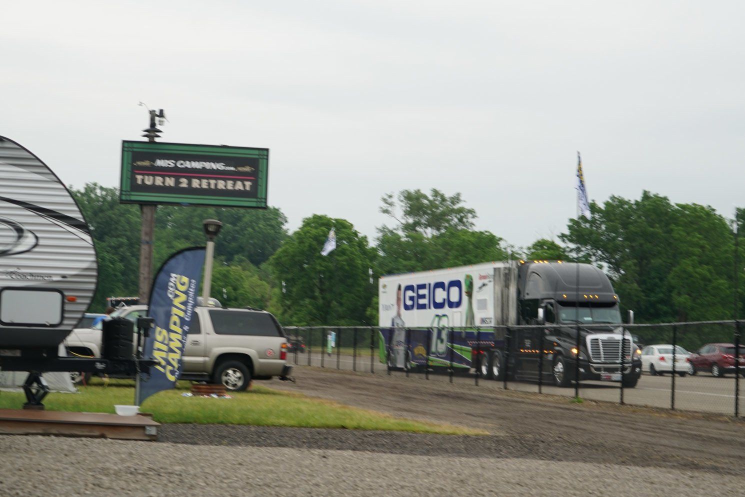 A geico truck is parked in a gravel lot