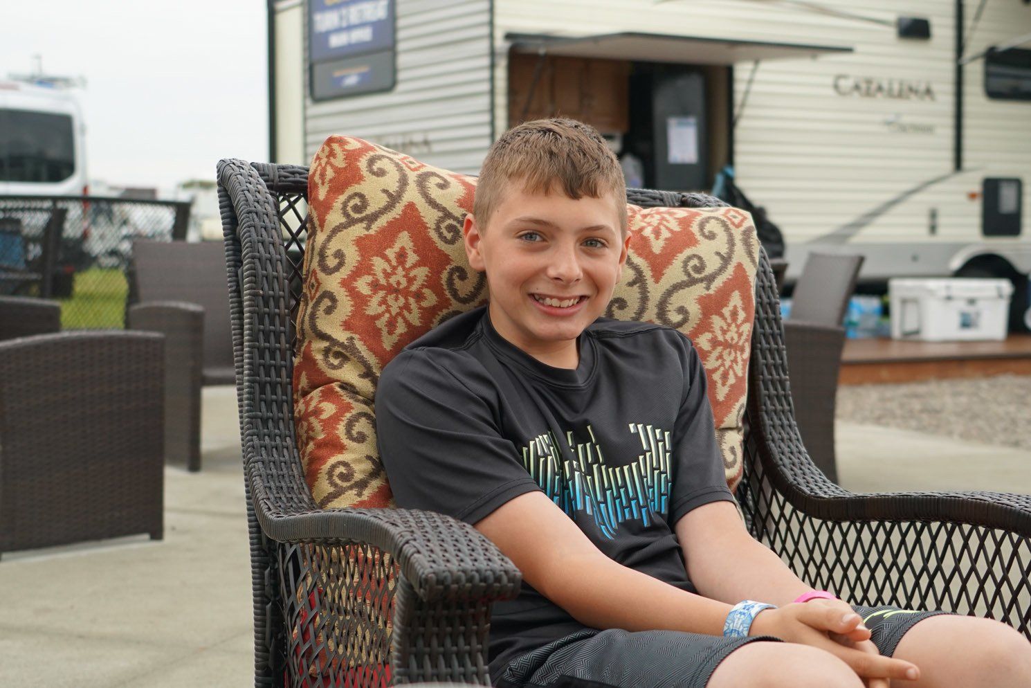 A young boy is sitting in a chair in front of a trailer.