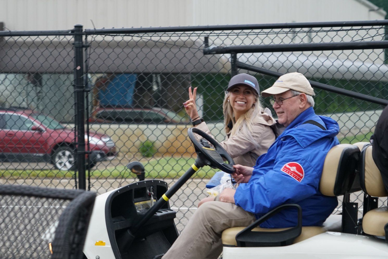 A man in a blue jacket is driving a golf cart
