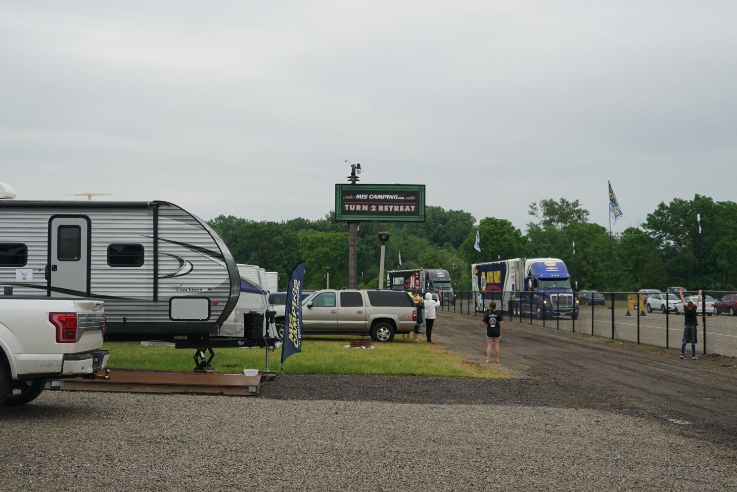 A truck is parked in a gravel lot next to a trailer.