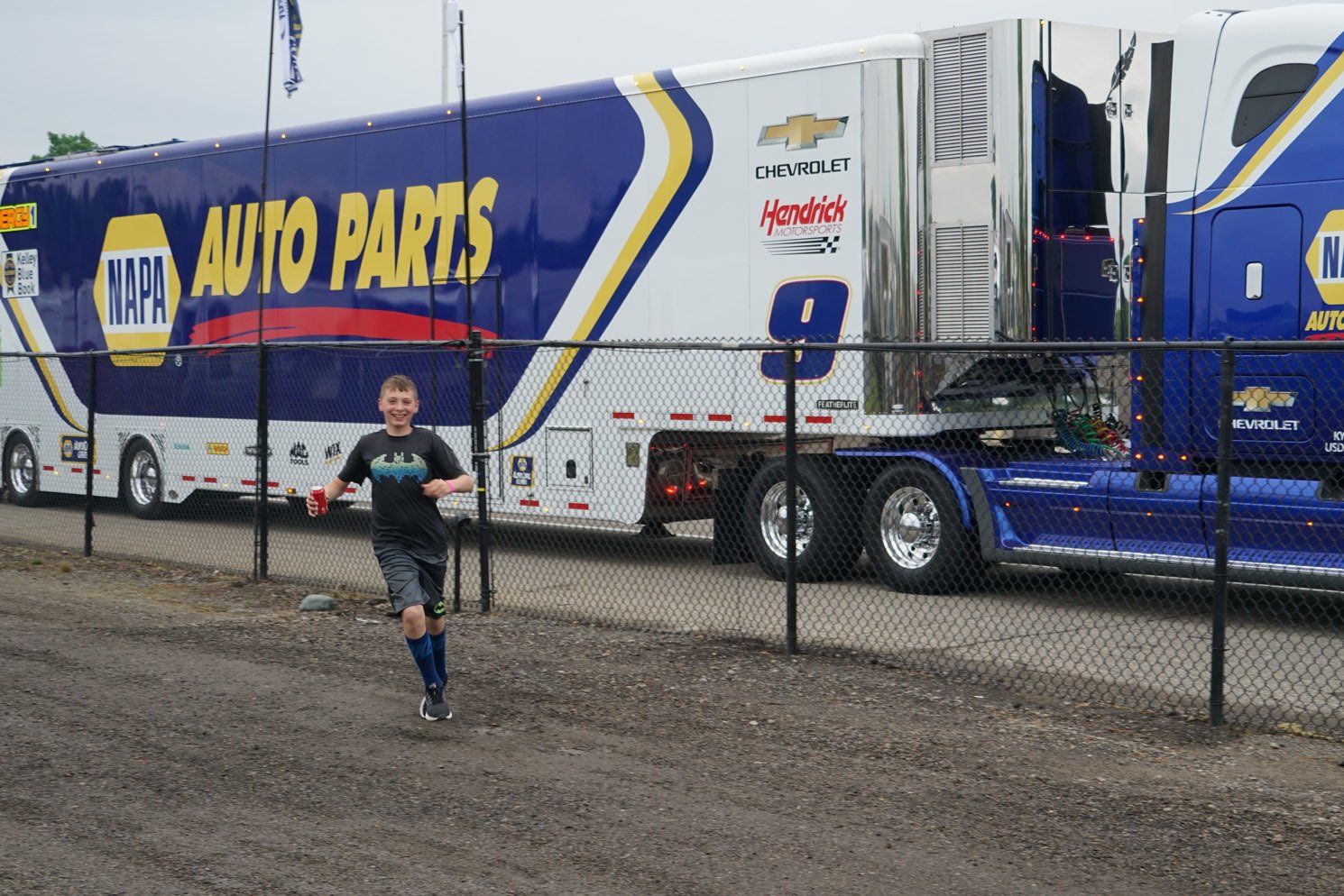 A boy running in front of a truck that says napa auto parts