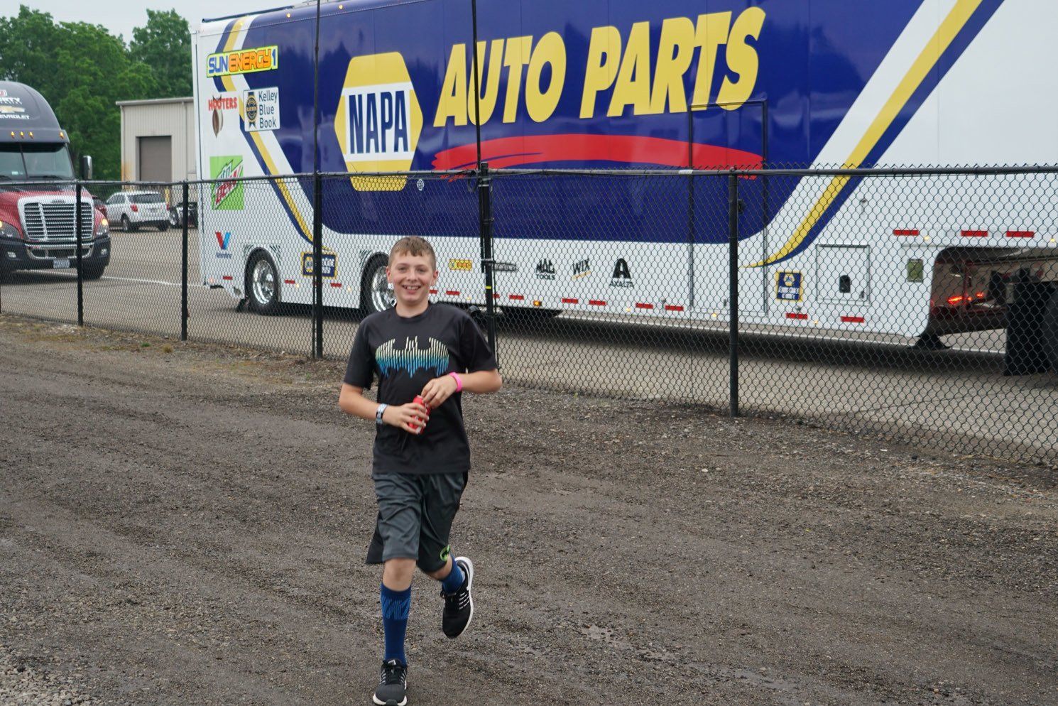 A boy is running in front of an auto parts truck