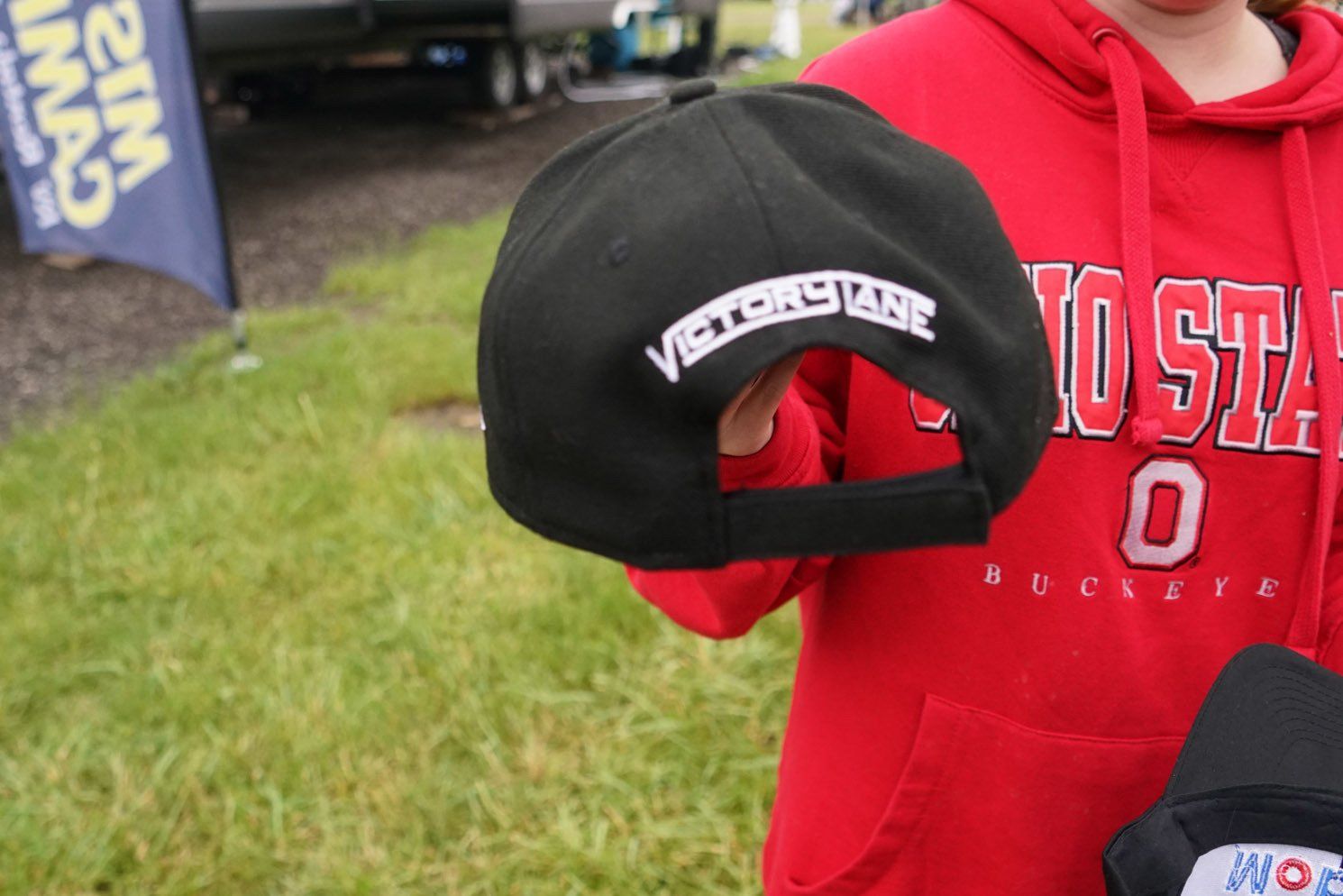 A person wearing a red buckeyes hoodie holds a black hat