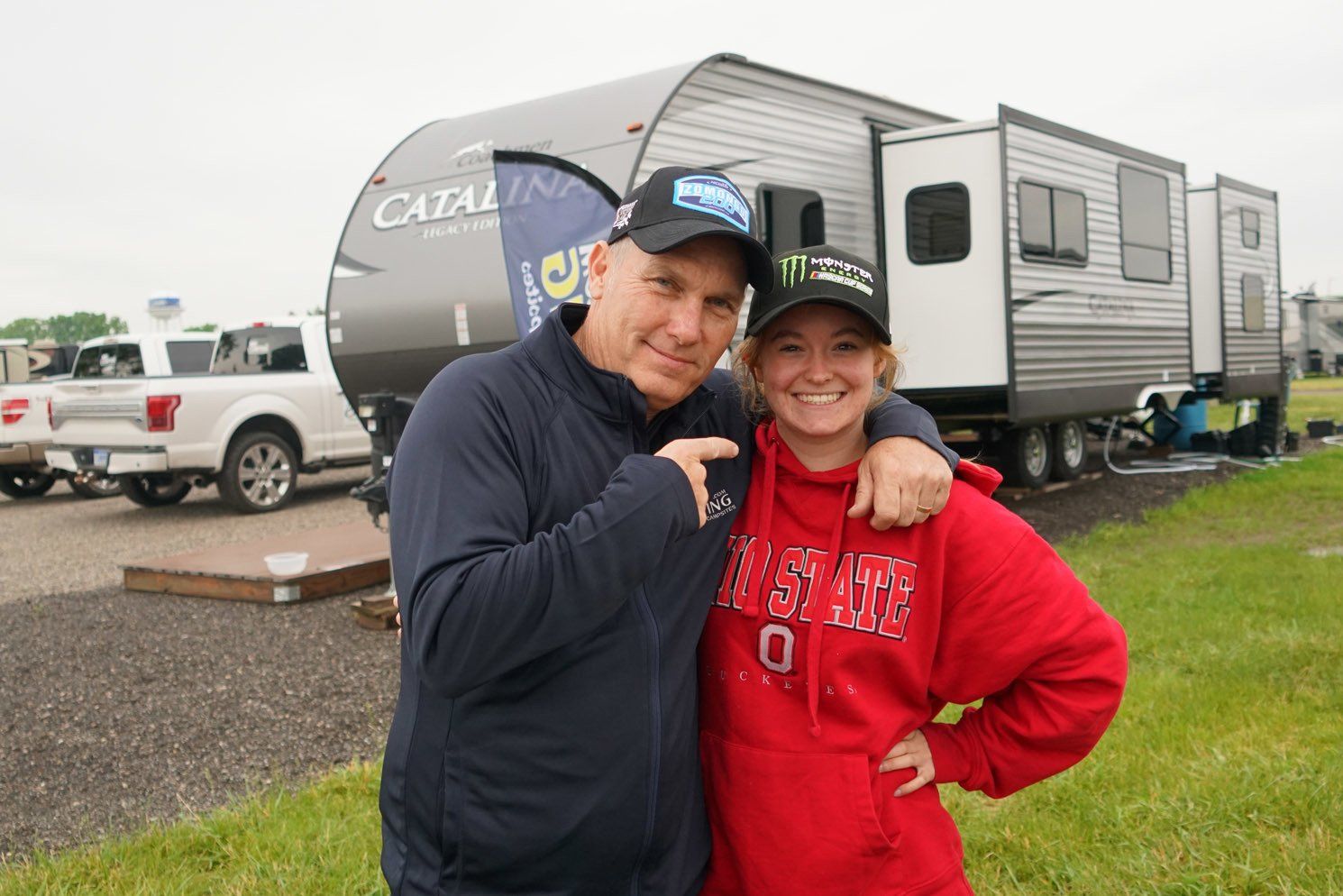 A man and a woman are posing for a picture in front of a trailer.