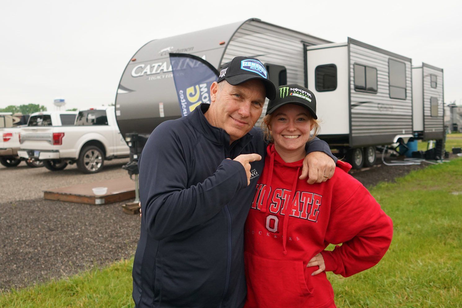A man and a woman are posing for a picture in front of a trailer.