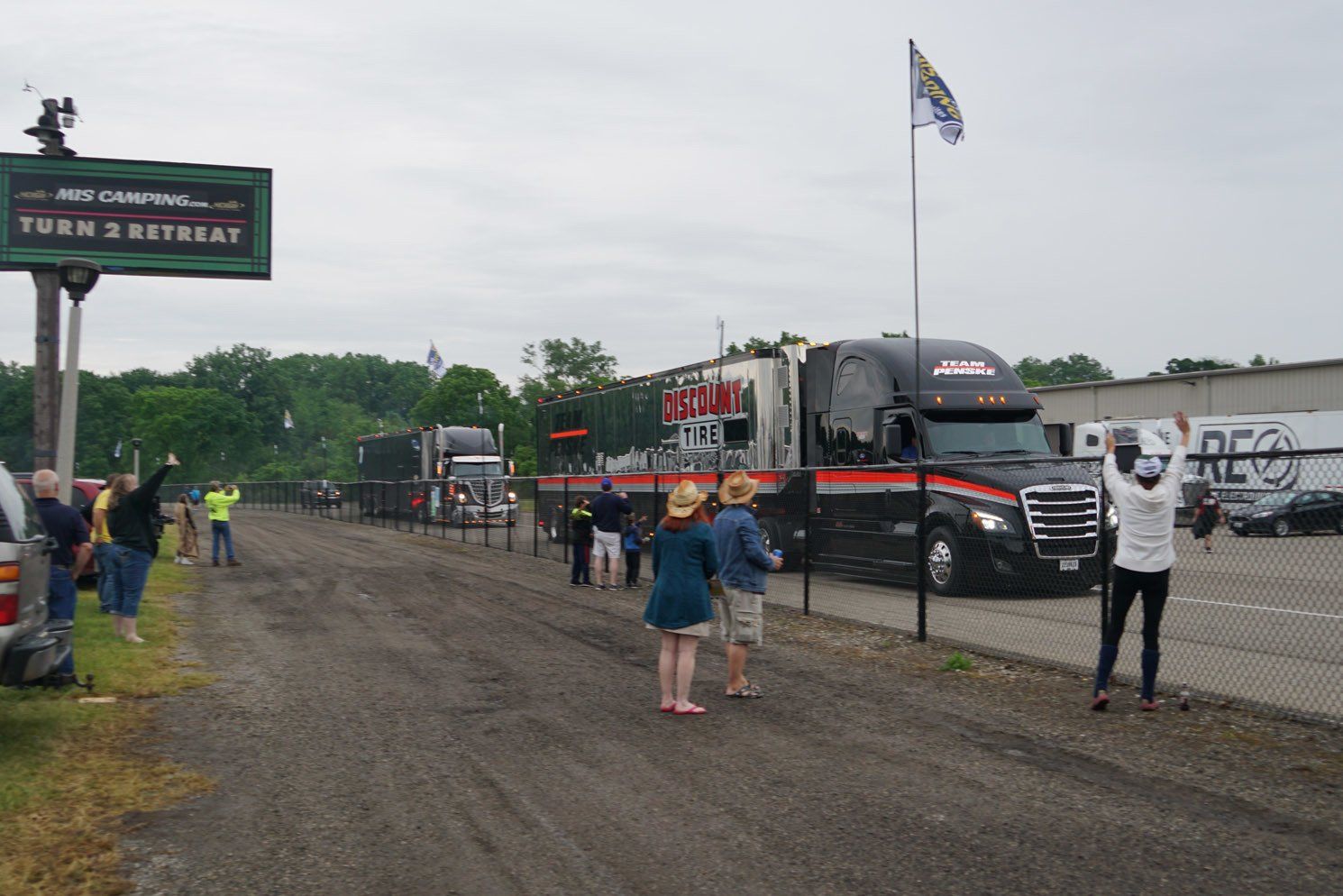 A group of people are standing in front of a truck that says turn 3 retreat