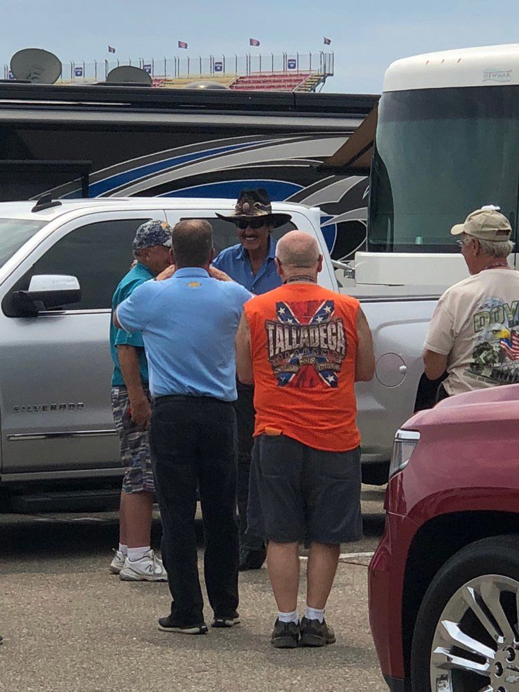 A group of men are standing around a truck talking to each other.